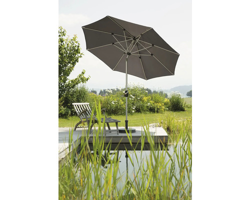 Umbrelă de soare pătrată pe o terasă de lemn cu șezlong lângă iaz