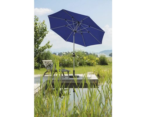 Umbrelă de grădină albastră lângă un iaz și o terasă din lemn cu șezlong