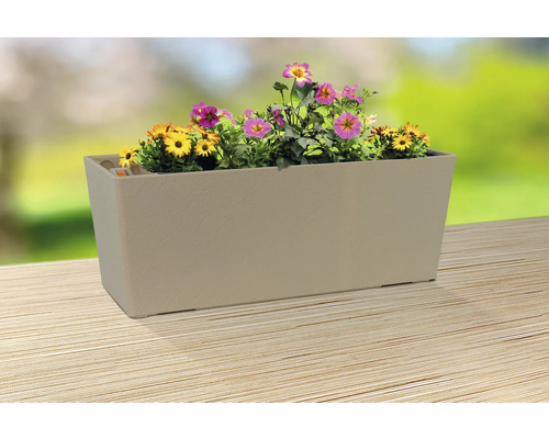 Jardinieră bej cu flori galbene și roz pe o masă