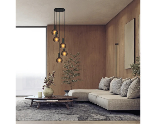 Cameră de zi cu canapea, masă și lampă suspendată cu mai multe lumini