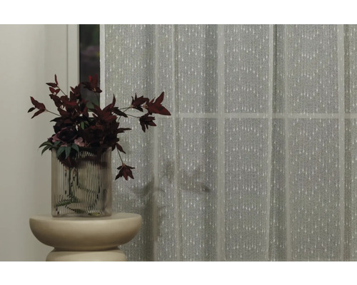 Cortină decorativă în fața ferestrei, completată de o vază cu flori pe o măsuță laterală.