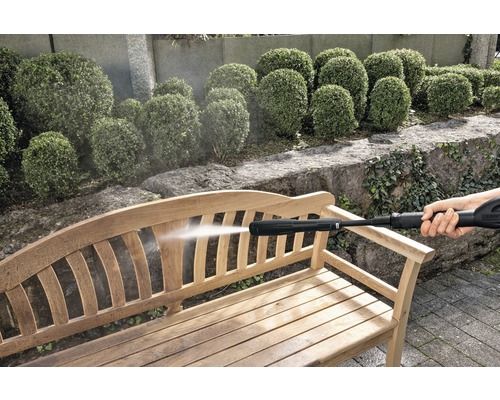 Curățător sub presiune utilizat pentru curățarea unei bănci de lemn în grădină