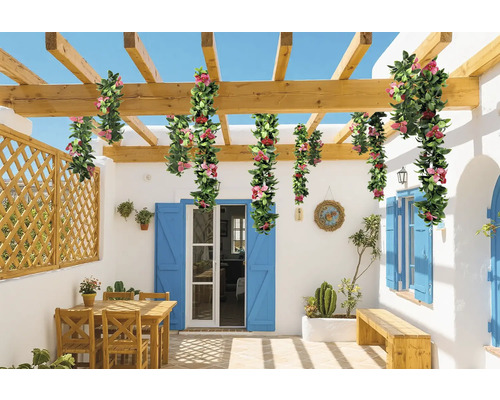 Spațiu exterior cu pergolă, decorat cu ghirlande de flori artificiale, cu zonă de relaxare și bancă.