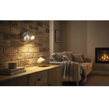 Living cu perete din cărămidă, comodă și lampă de perete cu două brațe