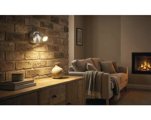 Living cu perete din cărămidă, comodă și lampă de perete cu două brațe