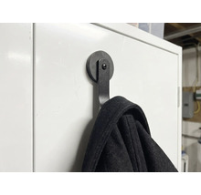 Cârlig magnetic negru pentru haine pe o suprafață albă cu o jachetă agățată