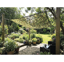 Grădină cu plasă de camuflaj ca protecție solară deasupra unei zone de relaxare