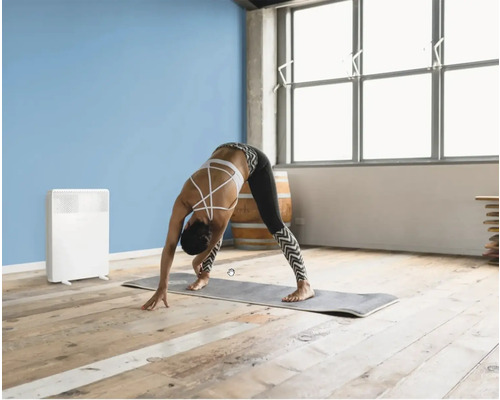 Scenă cu o femeie care face yoga pe o saltă într-o cameră cu un radiator.