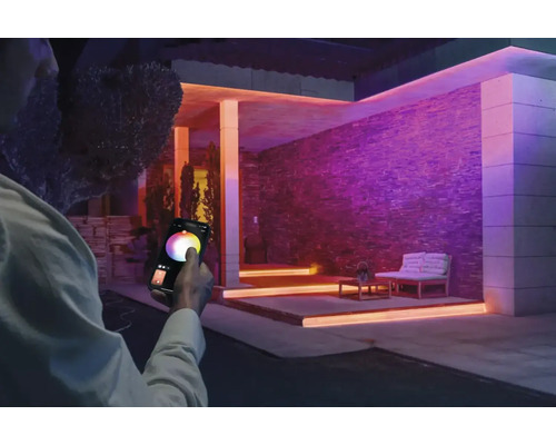 Casă cu iluminare colorată și persoană care controlează lumina cu un smartphone