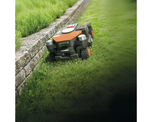 Robot de tuns iarba Landroid pe gazon lângă un zid