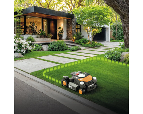 Robot de tuns iarba pe gazon în fața casei cu alee pavată