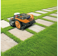 Robot de tuns iarba pe un gazon cu o potecă din plăci de piatră