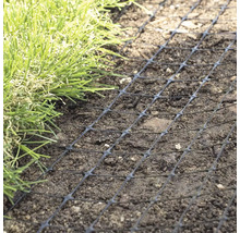 Grilaj negru de protecție a gazonului așezat pe pământ, lângă iarbă.