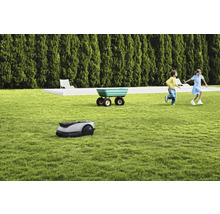 Scenă cu robot de tuns iarba, roabă și copii jucându-se pe gazon