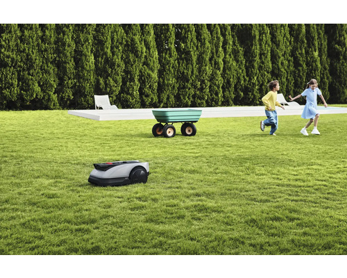 Scenă cu robot de tuns iarba, roabă și copii jucându-se pe gazon