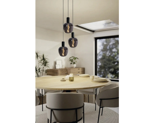 Trei lămpi suspendate cu becuri decorative deasupra unei mese de sufragerie