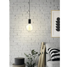 Lampa suspendată cu bec Edison în fața unui perete de cărămidă