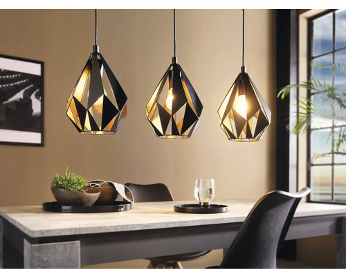 Trei lămpi suspendate geometrice din metal deasupra unei mese de sufragerie