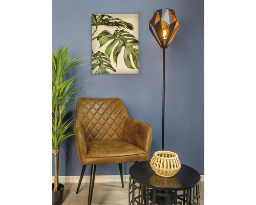 Scenă de living cu fotoliu, lampadar, masă și pictură murală