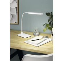 Birou cu lampă de birou, blocnotes, pix și pahar cu apă pentru o atmosferă de lucru luminoasă și organizată.