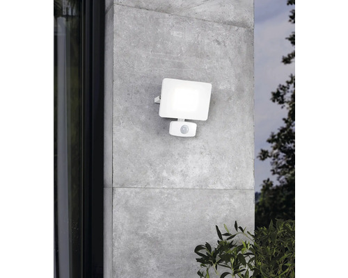 Lumină albă de exterior cu senzor de mișcare pe un perete gri