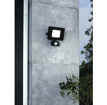 Reflector exterior LED negru cu senzor de mișcare montat pe un perete.