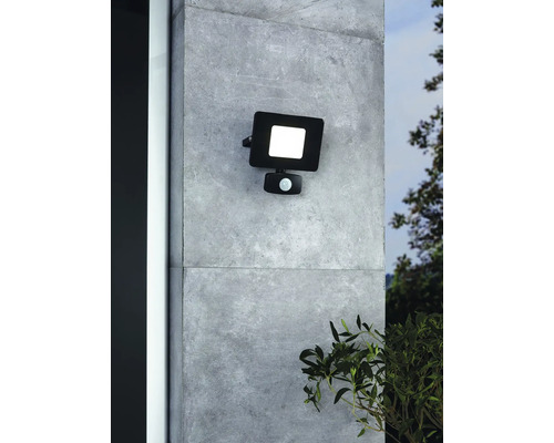 Reflector exterior LED negru cu senzor de mișcare montat pe un perete.