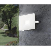 Lumină LED albă de exterior pe un perete lângă o grădină