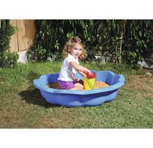 Fetiță se joacă într-o scoică de nisip albastră cu jucării de nisip în grădină.