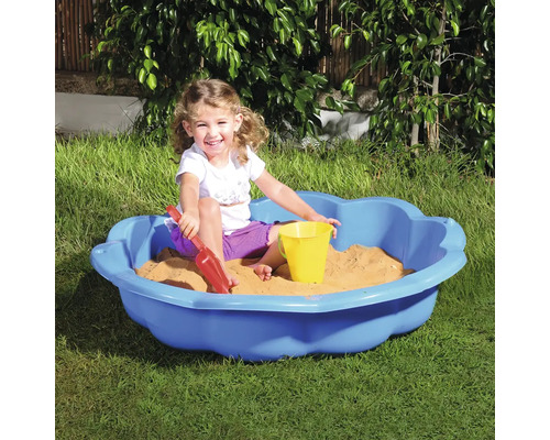 Copil se joacă într-o ladă cu nisip albastră cu jucării de nisip în grădină