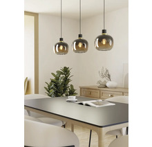 Trei corpuri de iluminat suspendate cu abajururi rotunde din sticlă deasupra unei mese de sufragerie.