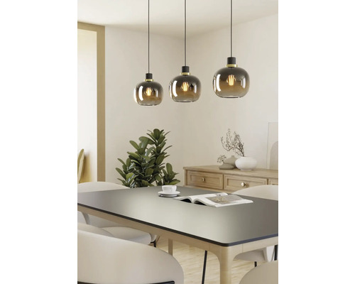 Trei corpuri de iluminat suspendate cu abajururi rotunde din sticlă deasupra unei mese de sufragerie.