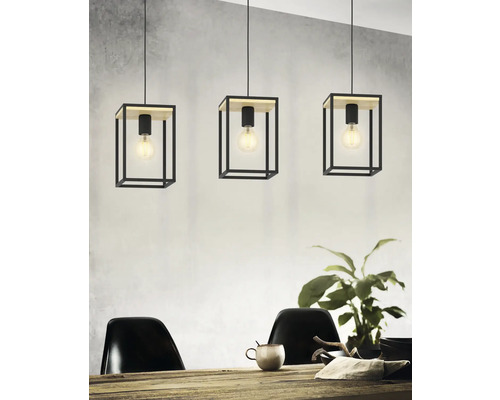 Trei lămpi suspendate cu abajururi cubice din metal și elemente din lemn deasupra unei mese de sufragerie.