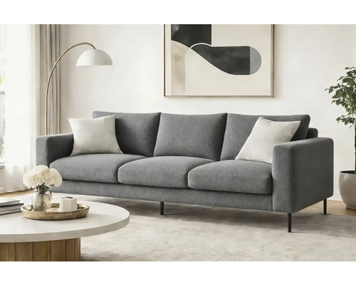 Canapea modernă cu trei locuri, cu material textil gri și picioare metalice subțiri, într-un living luminos și minimalist cu măsuță de cafea.