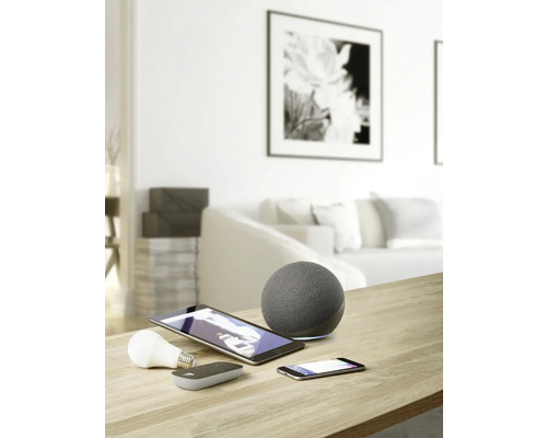 Imagine cu o cameră de zi cu dispozitive inteligente pentru casă, precum difuzoare, tablete, smartphone-uri și becuri pe o masă.