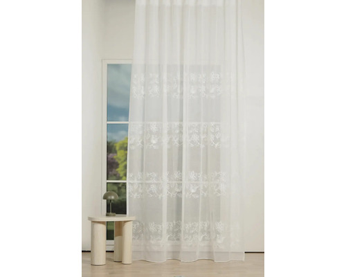 Draperie decorativă albă cu broderie florală în fața ferestrei