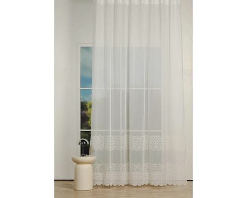 Perdea albă din voal cu model floral în fața ferestrei