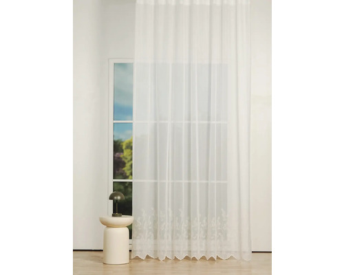 Perdea din material transparent cu broderie în fața unei ferestre