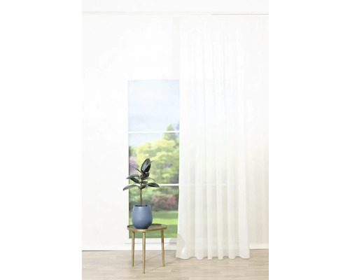 Plantă de interior decorativă în ghiveci pe o măsuță laterală lângă o fereastră cu perdea