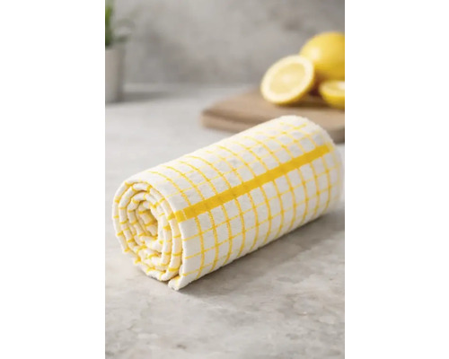 Prosop de bucătărie în carouri galben-alb, rulat pe un blat de bucătărie cu lămâi în fundal.