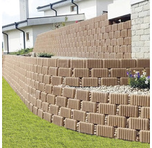 Zid de grădină în trepte din blocuri de beton striate pentru stabilizarea pantei lângă gazon.
