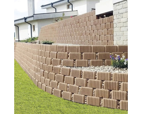 Zid de grădină în trepte din blocuri de beton striate pentru stabilizarea pantei lângă gazon.