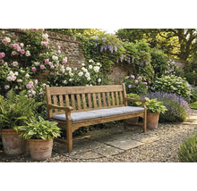 Bancă de grădină din lemn cu pernă într-o grădină înfloritoare