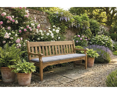 Bancă de grădină din lemn cu pernă într-o grădină înfloritoare