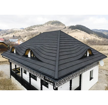 Casă cu acoperiș metalic și ferestre de mansardă în fața unui peisaj deluros