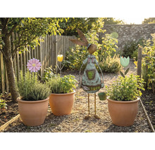 Scenă de grădină cu ghivece de teracotă plantate, suporturi pentru flori și un decor de grădină în formă de iepure