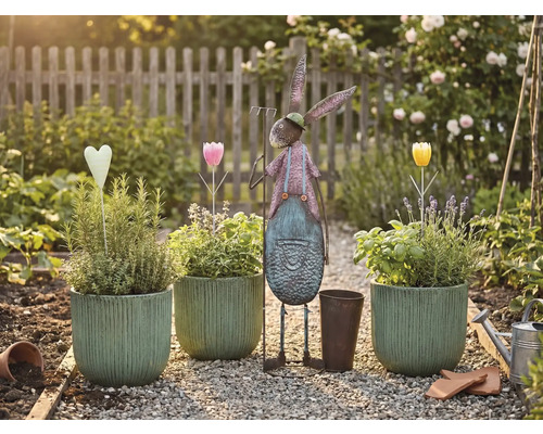 Scenă de grădină cu ghivece plantate, iepure metalic și decorațiuni pe o potecă de pietriș