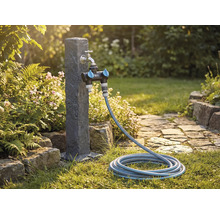 Scenă de grădină cu robinet de apă, distribuitor și furtun de grădină pe un gazon