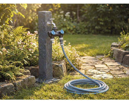 Scenă de grădină cu robinet de apă, distribuitor și furtun de grădină pe un gazon