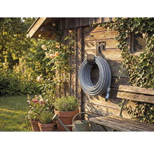 Scenă de grădină cu tambur pentru furtun pe perete de lemn, înconjurat de plante